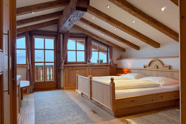 Schlafbereich der Suite Rettenstein mit Doppelbett, Altholzbalken und eigenem Balkon