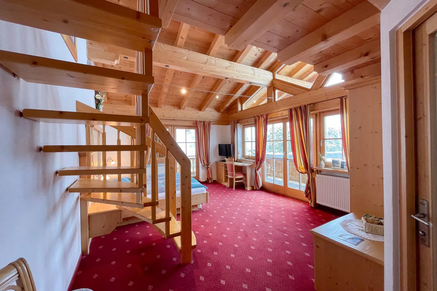 Blick von der Eingangstür in die zweistöckige Suite Panorama mit Holztreppe zur Galerie