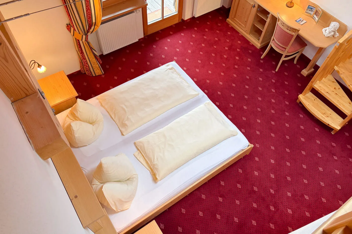 Blick von der Galerie auf den Schlafbereich der Suite Mountain mit Doppelbett, Schreibtisch und Balkonzugang