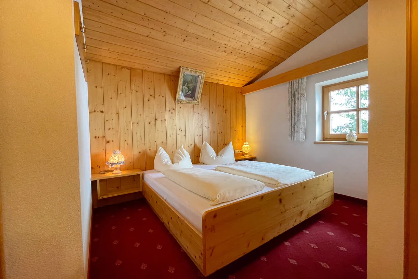 Schlafbereich im Ochsalm Zimmer mit Doppelbett, Holzverkleidung und Fenster
