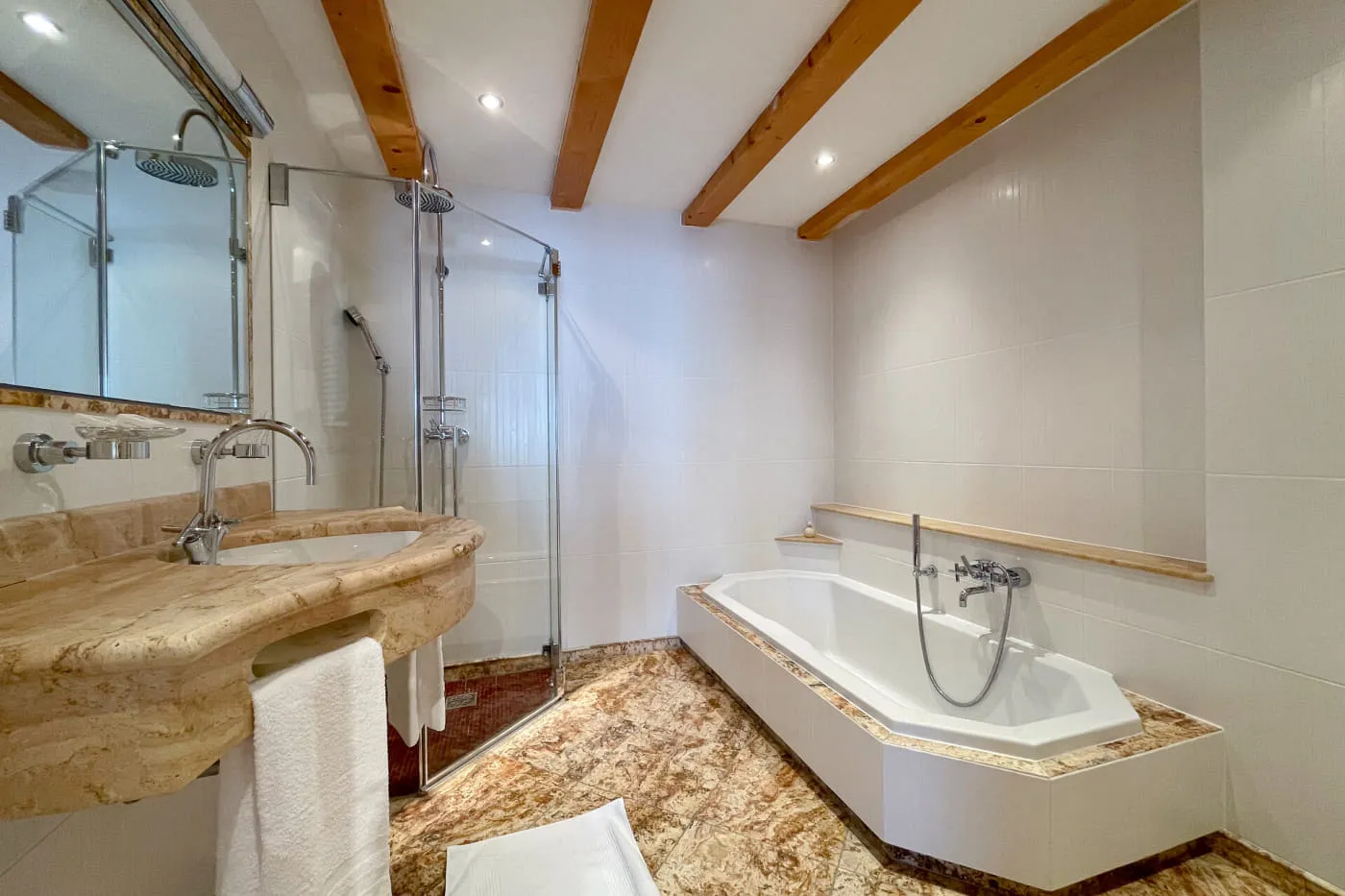 Badezimmer der Suite Ochsalm mit Badewanne, begehbarer Dusche und Waschtisch aus Naturstein