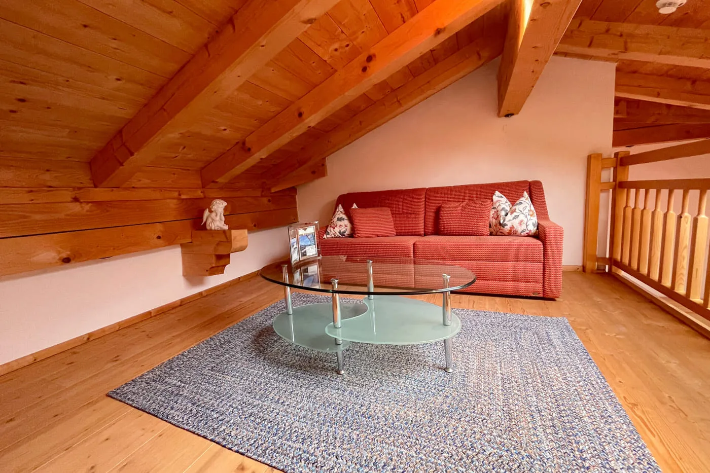 Gemütliche Sitzecke auf der Holzgalerie der Suite Ochsalm mit Sofa und Glastisch